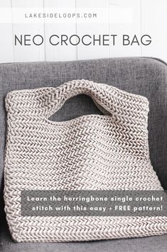 a crocheted bag sitting on top of a gray couch next to a white wall