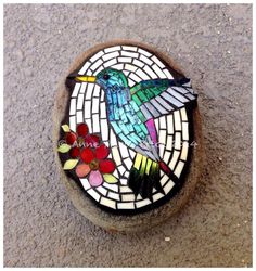 a bird painted on the side of a stone with flowers in it's beak