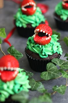 cupcakes with green frosting and red decorations on them, decorated like monsters