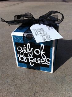 a gift box that has been decorated with black and white writing on it, tied to a ribbon