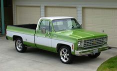 a green and white truck parked in front of a garage