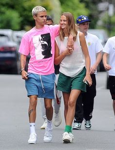 a man and woman walking down the street with one holding his hand out to another