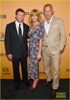 two men and a woman standing next to each other on a black carpet at an event