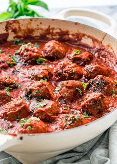 meatballs and sauce in a white pan on a table with a napkin next to it