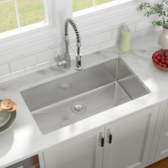 a stainless steel kitchen sink with faucet and soap dispenser on the counter