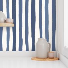 a blue and white striped wallpaper in a kitchen with a wooden tray on the counter