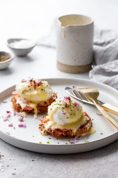 two eggs benedicts on a plate with silverware