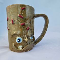 a coffee mug with an evil face on it's side and eyes painted on the inside