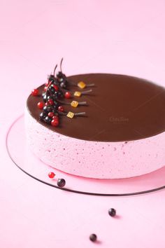 a cake with chocolate frosting and sprinkles sits on a pink surface