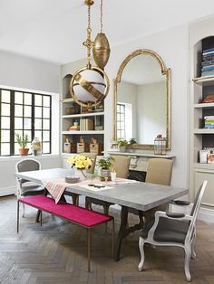 a dining room table with chairs and a bench in front of a large mirror on the wall