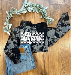 a black and white shirt with the word mama on it next to two pairs of jeans