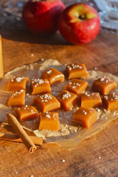 apples and cinnamon sticks on a cutting board next to an apple cider with salt in it