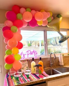 a kitchen with balloons and drinks on the counter