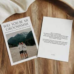 two people standing next to each other on top of a wooden table with an envelope