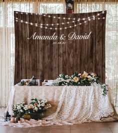 a table with flowers and lights on it in front of a wooden paneled wall