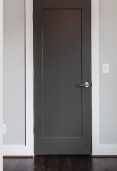 an empty room with a gray door and wood floors