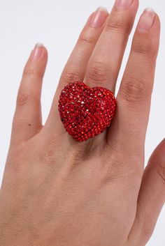 a woman's hand holding a red heart shaped ring