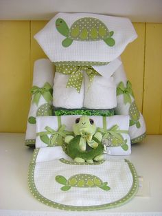 a stuffed turtle sitting on top of a pile of folded towels and blankets with green polka dots