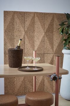 a wine glass sitting on top of a wooden table next to a vase and two stools