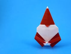 an origami red and white gnome's hat on top of a blue background