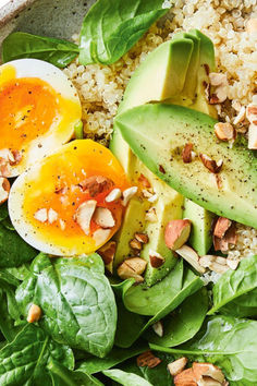 a bowl filled with spinach, avocado, eggs and nuts on top of rice