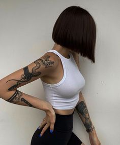 a woman with tattoos is leaning against a wall