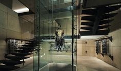 a glass staircase leading up to the top floor in a building with concrete walls and floors