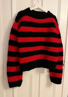 a red and black striped sweater hanging on a door