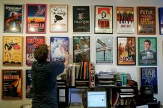 a man standing in front of a wall full of movie posters