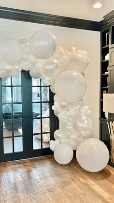 white balloons are hanging from the ceiling in front of a black door