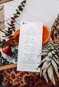 an orange slice sitting on top of a piece of paper next to pineapples