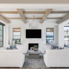 a living room with white couches and a flat screen tv mounted on the wall