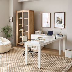 a white desk sitting in the middle of a living room next to a book shelf