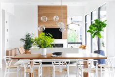 a dining room table with chairs and plants in the center, next to a fireplace