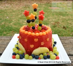 a cake with fruit on it sitting on a wooden table in front of some grass