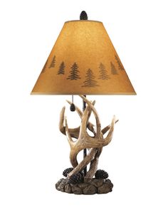 an antler lamp with pine trees on it and a shade over the table top