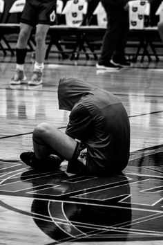 a man sitting on top of a basketball court