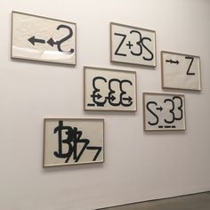 four black and white paintings hanging on the wall next to each other with arrows pointing in different directions