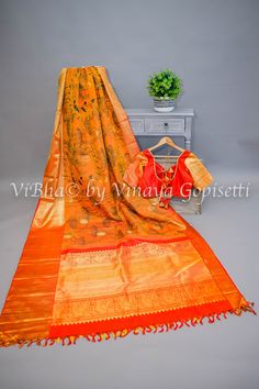 Add a touch of timeless elegance to your wardrobe with our Rust and Red Kanchi Pen Kalamkari Silk Saree And Blouse. Crafted from luxurious silk, this saree is bright and beautiful, making it the perfect addition to any special occasion. Elevate your fashion game and exude a sense of sophistication with this exquisite piece. The accompanying saree blouse is tailored with handcrafted doris and tassels. The attention to detail further enhances it and gives the blouse a great finish.. Designer Raw Silk Orange Saree, Orange Tussar Silk Anarkali, Orange Silk Traditional Wear For Transitional Season, Transitional Orange Silk Traditional Wear, Festive Orange Tussar Silk Blouse Piece, Orange Tussar Silk Blouse Piece For Wedding, Designer Orange Blouse Piece With Zari Weaving, Anarkali Orange Raw Silk Saree, Orange Silk Saree For Transitional Season