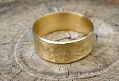 a gold wedding ring sitting on top of a tree stump