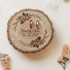 two wedding rings are placed on top of a tree slice