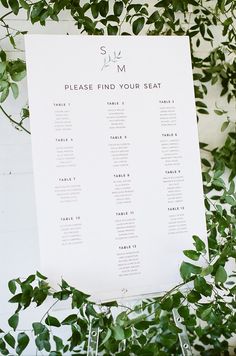 a seating chart is displayed on a table surrounded by greenery