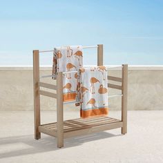 two towels are hanging on a towel rack near the beach and water in the background