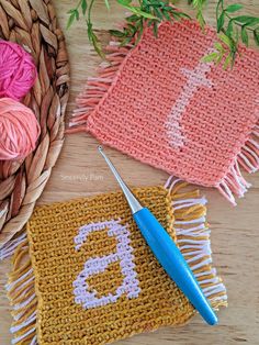 three crocheted items are sitting on a table next to a basket with yarn