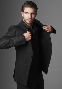 a man in a black suit is adjusting his jacket