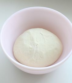 a bowl filled with dough sitting on top of a table next to a white counter