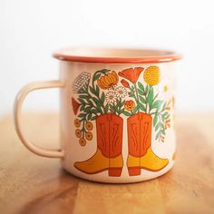 an orange and white coffee mug with boots on the inside sitting on a wooden table