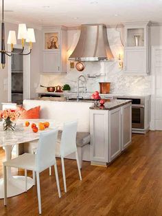 a kitchen with white cabinets and marble counter tops, an island in the middle is surrounded by chairs