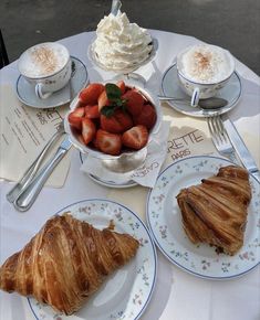 there is a croissant, strawberries and other food on the table with silverware