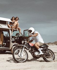 a man riding on the back of a motorcycle next to a woman sitting on top of a van